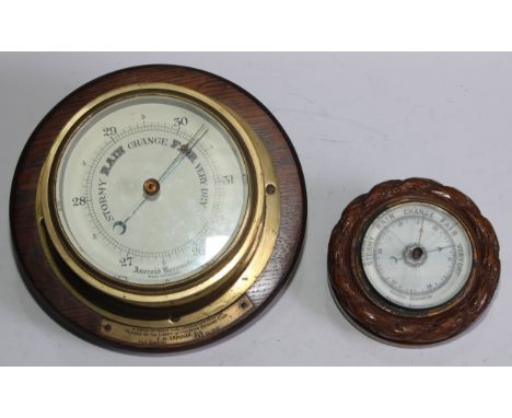 A mid 20th century brass aneroid wall barometer, mounted on oak, 25cm diameter; another aneroid wall barometer with carved ro