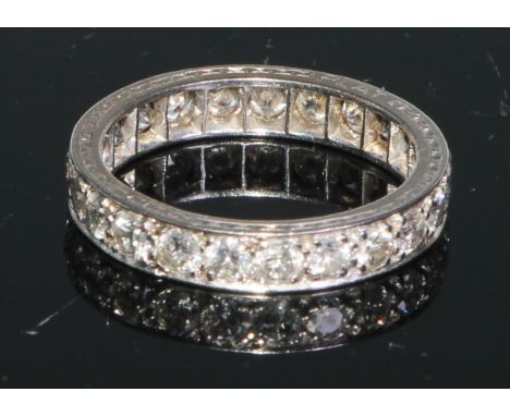A diamond and white metal eternity ring, a continuous band of brilliant cut stones, engraved with a bright cut band, size R, 