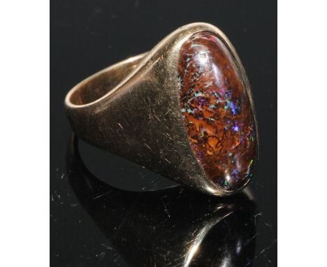 A black opal and 9ct gold ring, the large elongated oval cabochon stone set within within a plain shank, stamped 9ct, 15g gro