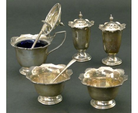 A silver cruet set by William Hutton & Sons comprising of a mustard pot with blue glass liner, two silver salts and two small