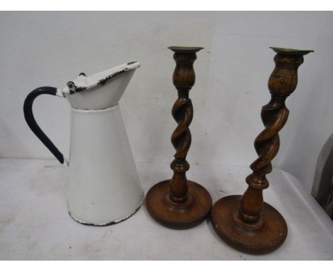 An enamel jug and a pair of treen candlesticks