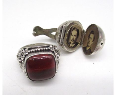 Silver Indonesian style ring set with cabochon red stone, stamped 925, and an early c20th silver orb fold out locket, filled 