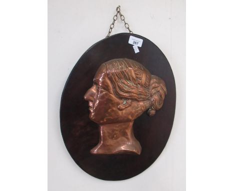 Early C20th embossed copper bust portrait of young woman, on oval figured mahogany plaque , with possible makers monogram, W3