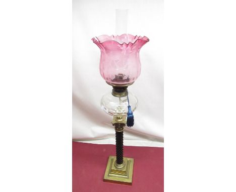 Late C19th oil lamp with etched cranberry tinted shade, spherical faceted clear glass reservoir on corinthian column with squ