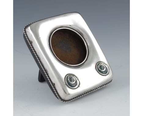 Archibald Knox for Liberty and Co., an Arts and Crafts silver and enamelled watch holder, Birmingham 1909, cushioned rectangu