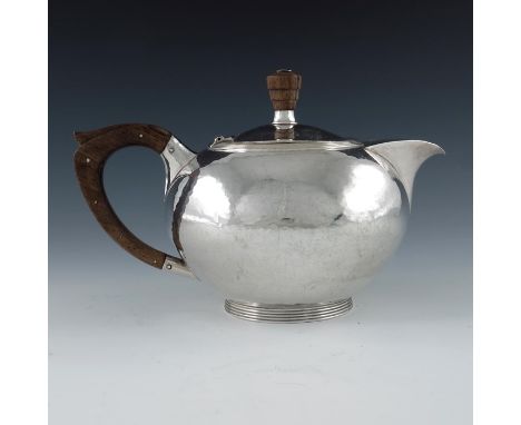 An Arts and Crafts silver teapot, AHJ, Birmingham 1945, planished oboid form on reeded cylindrical foot, streamlined ogee spo