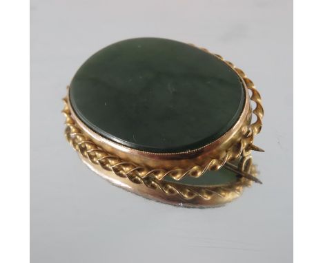 A Victorian gold mounted jade brooch, Imperial type oval within a ribbon twist border, 7cm x 3cm