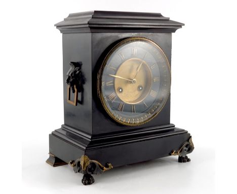 A late 19th Century black slate mantel clock with cicular gilded dial with Roman Numerals, and side lion's mask handles, insc