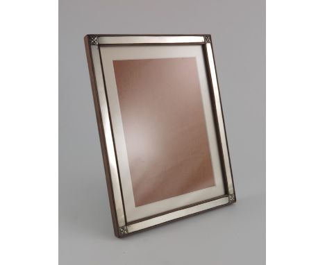 An Arts and Crafts silver and rosewood photo frame, rectangular form, the corners embossed with foliate motifs, easel back, s