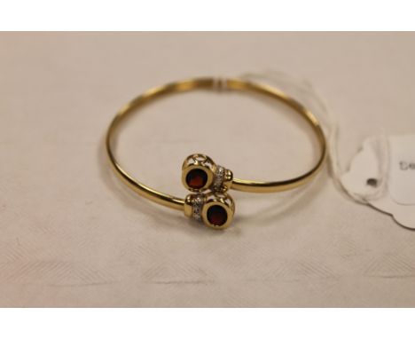 A 9ct gold bangle set with two diamonds and garnets. CONDITION REPORT: Good condition.