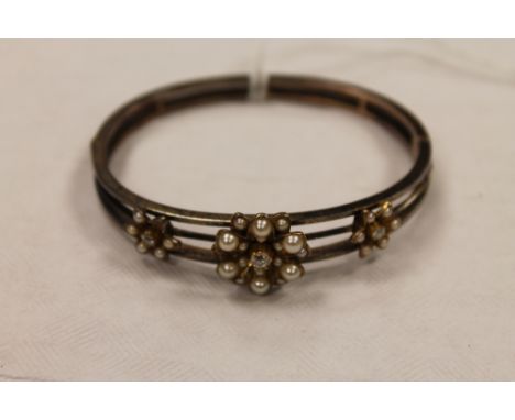 A diamond and pearl cluster bangle. CONDITION REPORT: Missing two small split pearls, the clasp requries attention, the yello