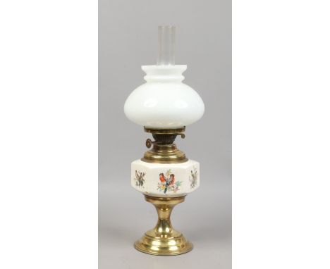 An early 20th century oil lamp with opaque glass shade and pottery font, hand painted with different species of birds and rai