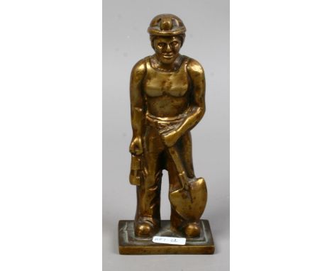 A bronze figurine of a miner holding a lamp and coal shovel.