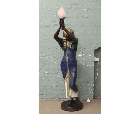 A large composite figure lamp formed as an Egyptian woman holding a flaming torch.