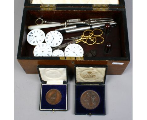 An antique mahogany box containing collectables including pocket watch movements, two cased bronze rifle medals, miniature ha