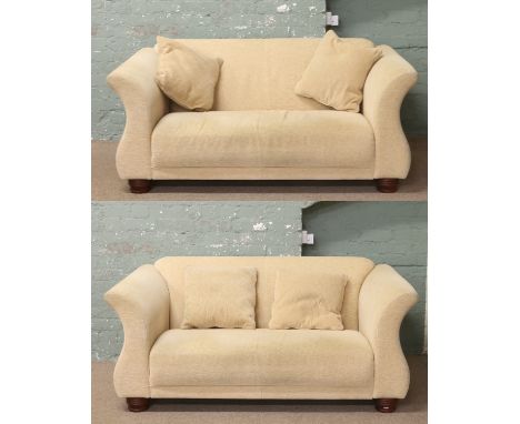 A matching pair of light upholstered two seat sofa raised on circular hardwood feet.