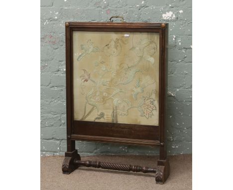 A Victorian mahogany firescreen double sided one side with a silkwork embroidery of flowers and birds the other a woolwork of
