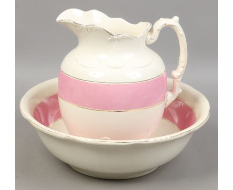 An early 20th century pottery wash jug and bowl with pink enamel and gilt decoration