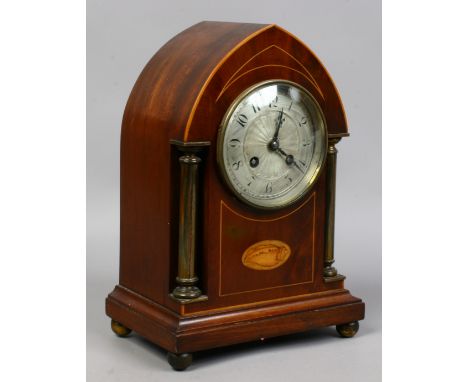 An Edwardian mahogany lancet clock with shell Patera inlay and silvered dial.