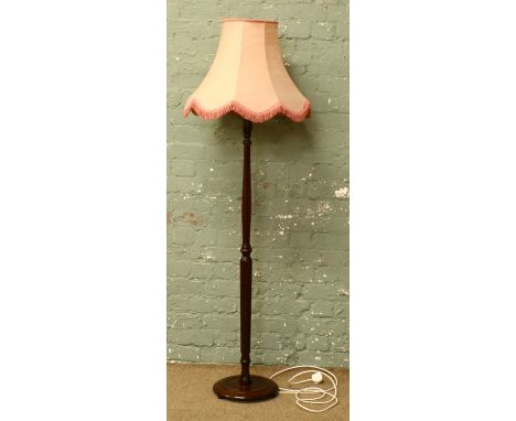A mahogany standard lamp with circular base.