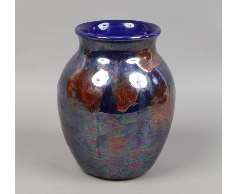 A Poole pottery vase decorated with iridescent orange and blue glazes.