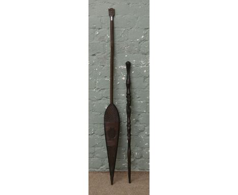 A carved oceanic style paddle along with a carved hardwood stick. Paddle length 125cm Stick length 87cm.