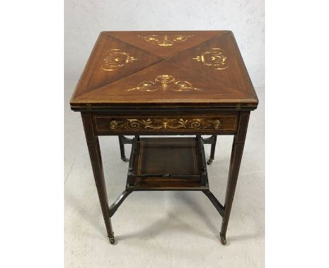 Victorian games table with tapering legs on original castors, with galleried shelf below, table top twists and quadrants open