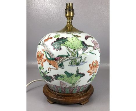 Oriental ceramic lamp base depicting lotus flowers, dragonflies and birds, on wooden stand, approx 33cm in height