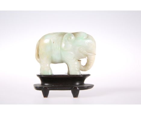 A CHINESE CARVED JADE MODEL OF AN ELEPHANT, probably 19th Century, on a hardwood stand. Jade 7.3cm long, 5.5cm high, 220 gram