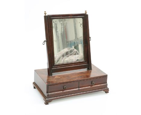 A GEORGE III MAHOGANY TOILET MIRROR, the rectangular mirror plate in a reeded frame, the base with two drawers and ogee brack