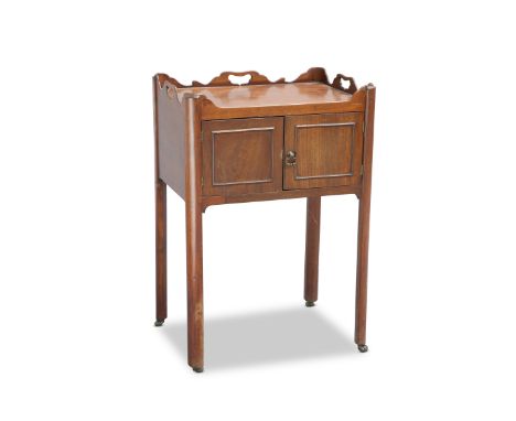 A GEORGE III CHIPPENDALE STYLE MAHOGANY BEDSIDE CUPBOARD, the wavy tray top with three cut-out handles, above a pair of cupbo
