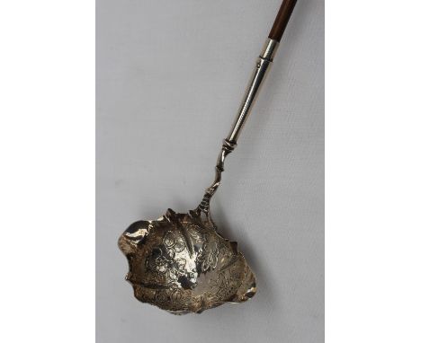 A Victorian silver ladle with a ring turned wooden handle, the bowl of oval form decorated with flower heads and leaves, Lond