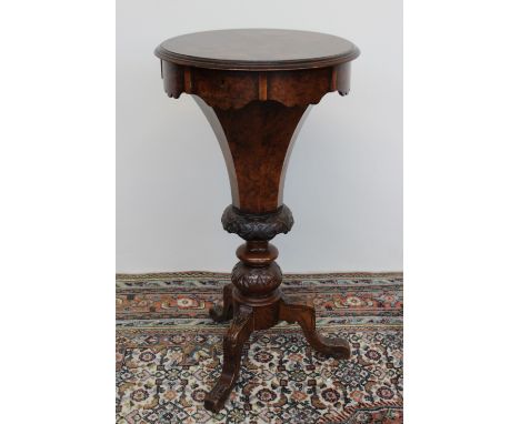 A Victorian walnut work table, the circular hinged top enclosing a compartmented interior on a tapering octagonal column and 