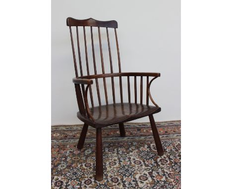 A 19th century stick back Windsor chair with a shaped cresting rail, hoop shaped arms and solid seat on tapering legs, 86cm h