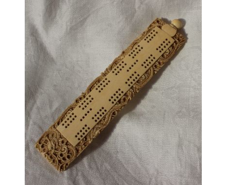 A late 19th / early 20th century Chinese ivory cribbage board carved with a dragon, the screw top containing markers, 18 x 4.