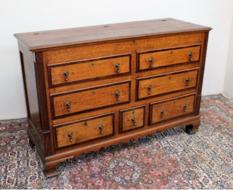 An 18th century oak coffer, the hinged rectangular planked top above four dummy drawers and three drawers on bracket feet, 13