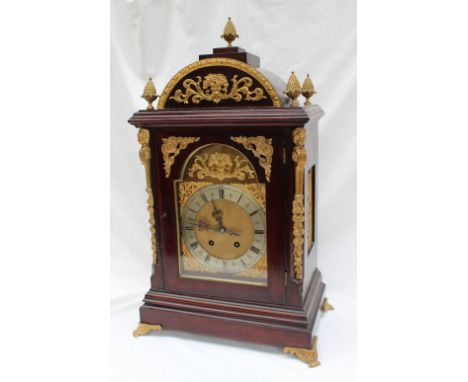 A gilt metal mounted mahogany bracket clock with a domed top and pineapple finials, above a glazed door enclosed between pill