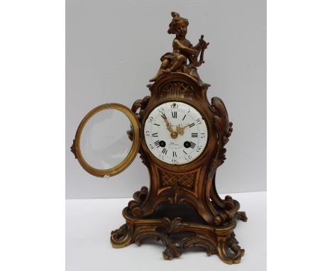 A French ormolu mantle clock, with a cherub surmount, scrolling leaves and swags, the circular enamel dial with Roman numeral