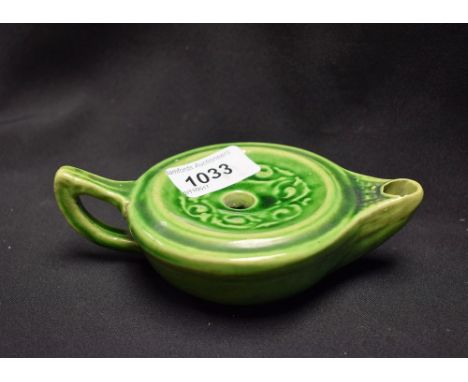 An art pottery novelty inkwell, as a Roman lamp, moulded with scrolls and glazed in tones of mottled green, 15cm wide, marked