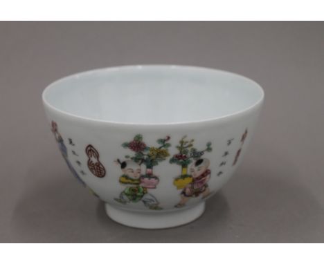 A Chinese porcelain bowl painted in bright enamels with boys in various pursuits, numerous seal marks and calligraphy, and se