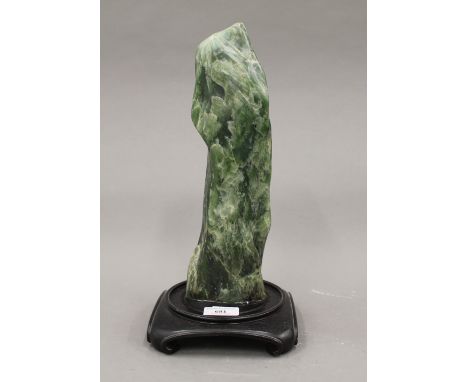 A Chinese green jade scholars rock, fitted to later base. 34 cm high overall.