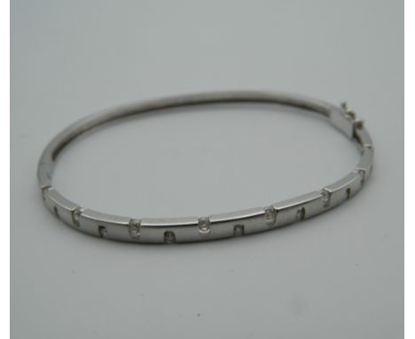 A 9 ct white gold bangle set with diamonds. 6.5 cm wide (9.1 grammes total weight)