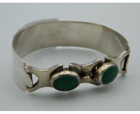 A silver bangle set with malachite. 6 cm wide.