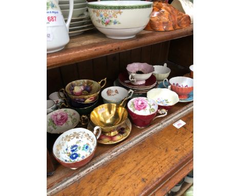 A shelf of mainly Aynsley cups and saucers including fruit pattern 