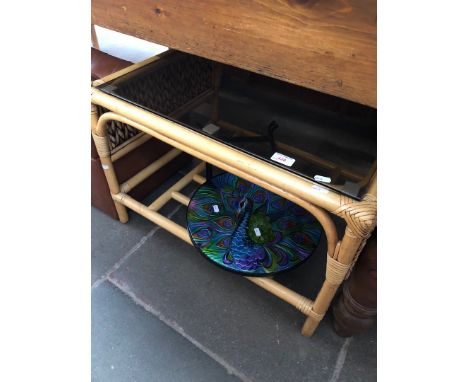 Three items of furniture comprising a retro pouffe, a glass top cane table and a folding metal table with peacock design to t