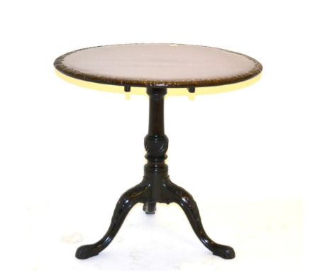 A Carved Mahogany Tripod Table, in George II style, the circular tilt-top with leaf carved edge, raised on a gun barrel and p