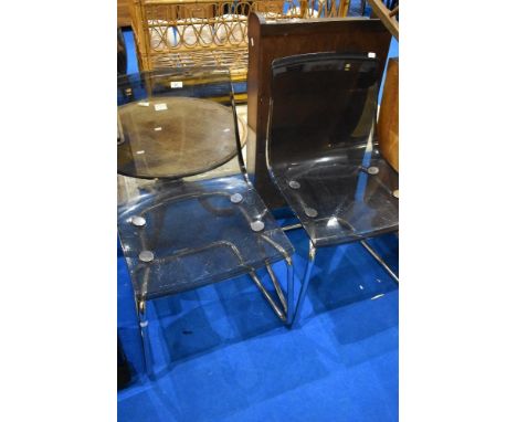 A pair of vintage chrome frame dining chairs with smokey perspex seats