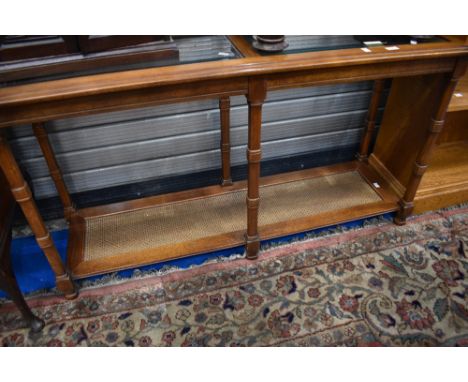 A modern hardwood console table having glass top and cane undertier, approx dimensions W133 D41 H70cm