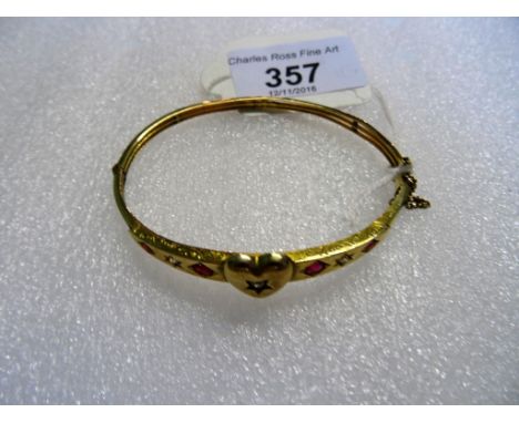 A late Victorian yellow metal bangle, the central heart shaped motif set with a round cut diamond, flanked on each side by tw