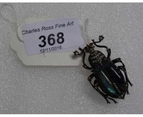 A white metal brooch formed as a large beetle in the manner of Fabergé, the wings opalescent green, the body set with seed pe